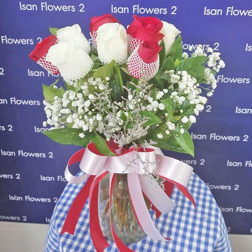 5 red and 4 white big roses with filler in vase a pre